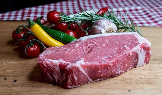 Rumpsteak mit Gem&uuml;se und Rosmarinzweig auf Holzbrett